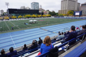 Photo of the OREP awards at Varsity Stadium. Staff are sitting in the bleachers looking onto the field where awards are being announced.