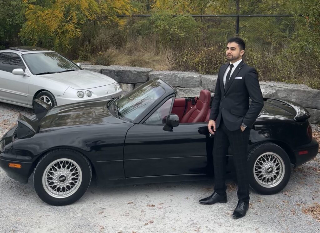 Safi Wakeely standing in front of a black convertable.