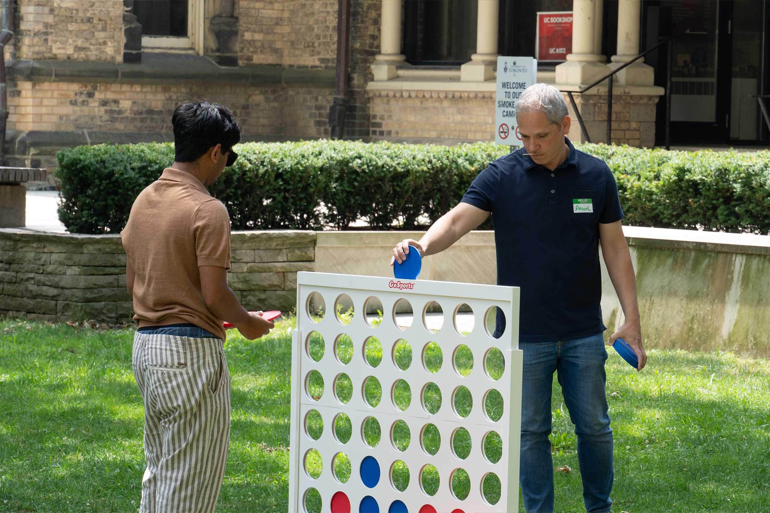 Two people playing a giant connect 4 game on the lawn